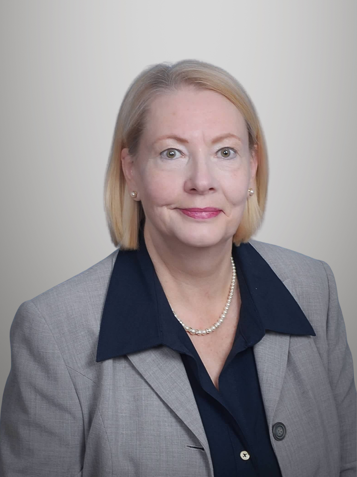 Portrait of a middle aged woman with blonde hair and a blue shirt, against a blue background