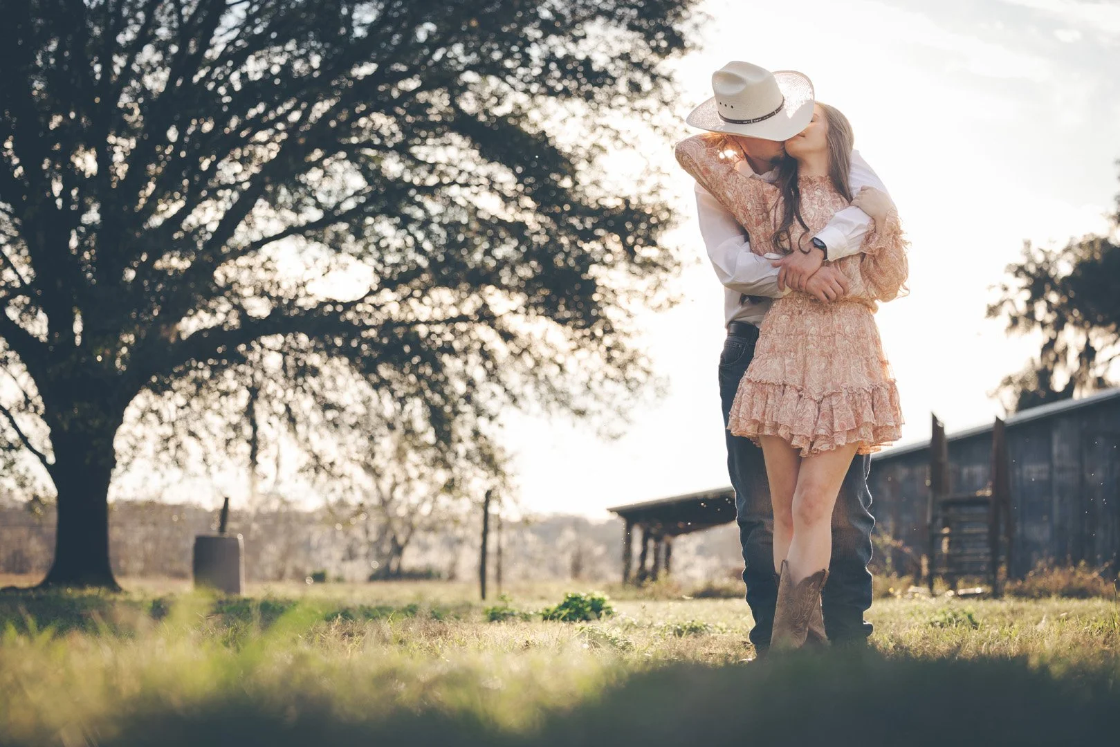 Couple in cowboy attire kissing outdoors