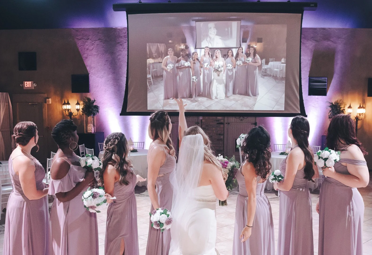 Bridal party watching a projection of a group photo at a wedding reception.