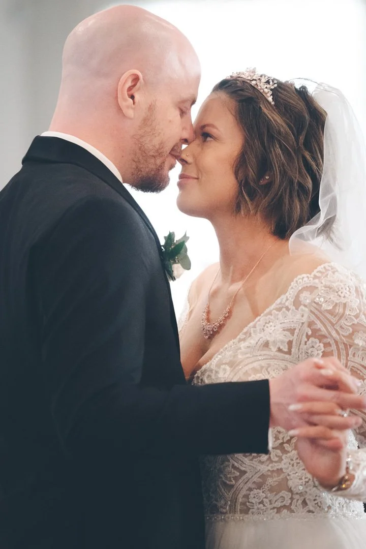 Bride and groom close together, smiling, during a wedding dance.