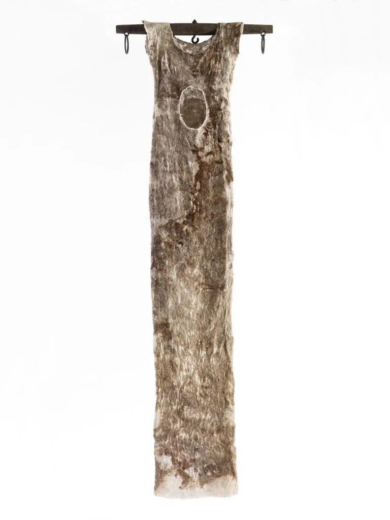 A long, narrow, weathered animal hide hanging from a wooden rod.
