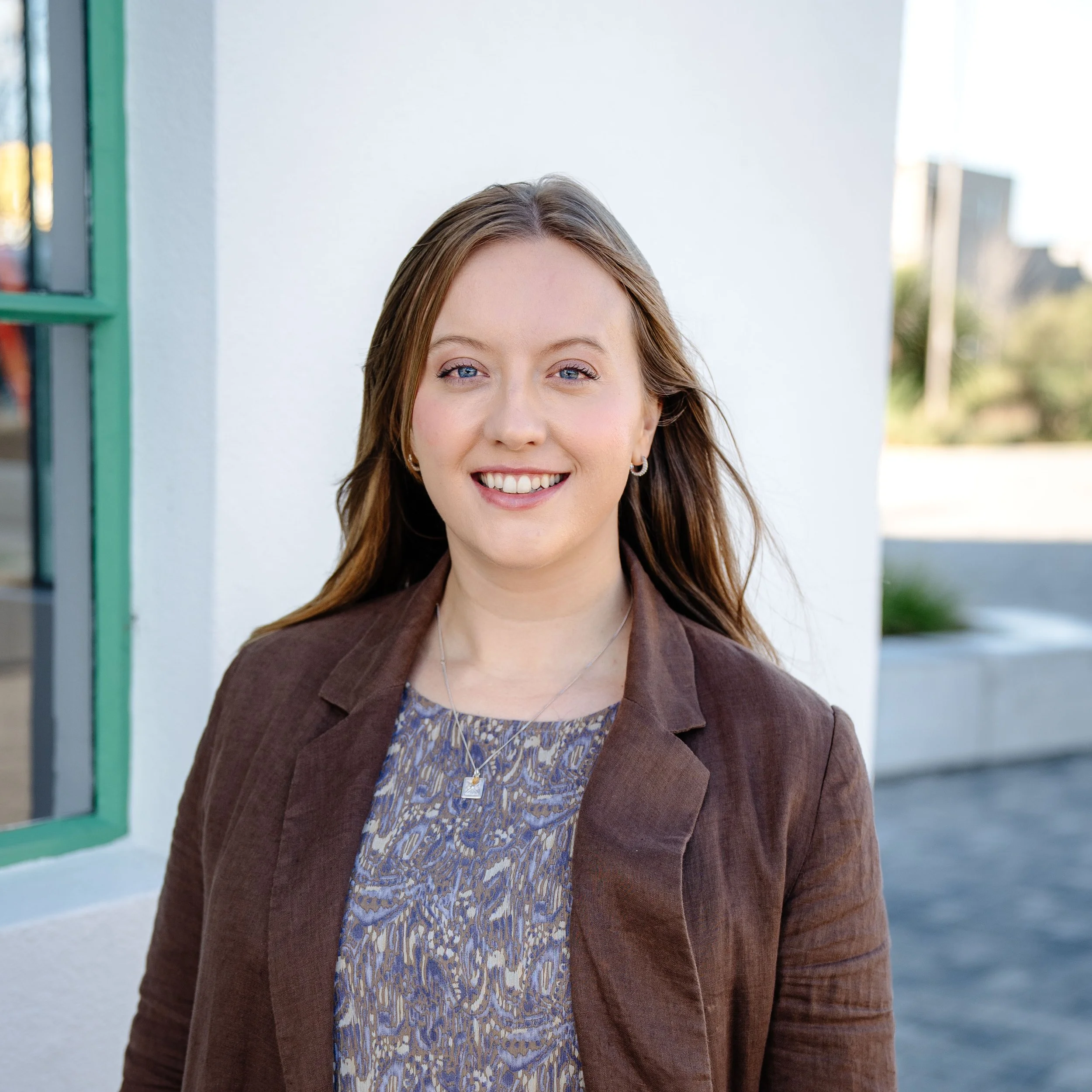 Head shot of Josie Cochrane smiling wearing a bright red shirt with native bushes in background