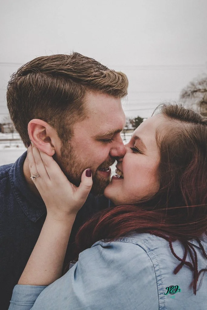 Close-up of a couple with their noses touching, smiling, and embracing outdoors on a cloudy day. Engagement photoshoot.