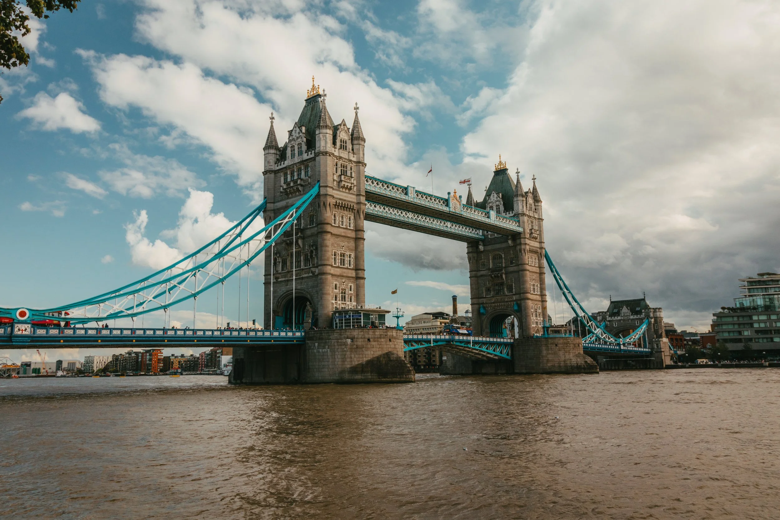 The Tower Bridge in London, England, seen from the River Thames with a partly cloudy sky. Landscape photography. United Kingdom.