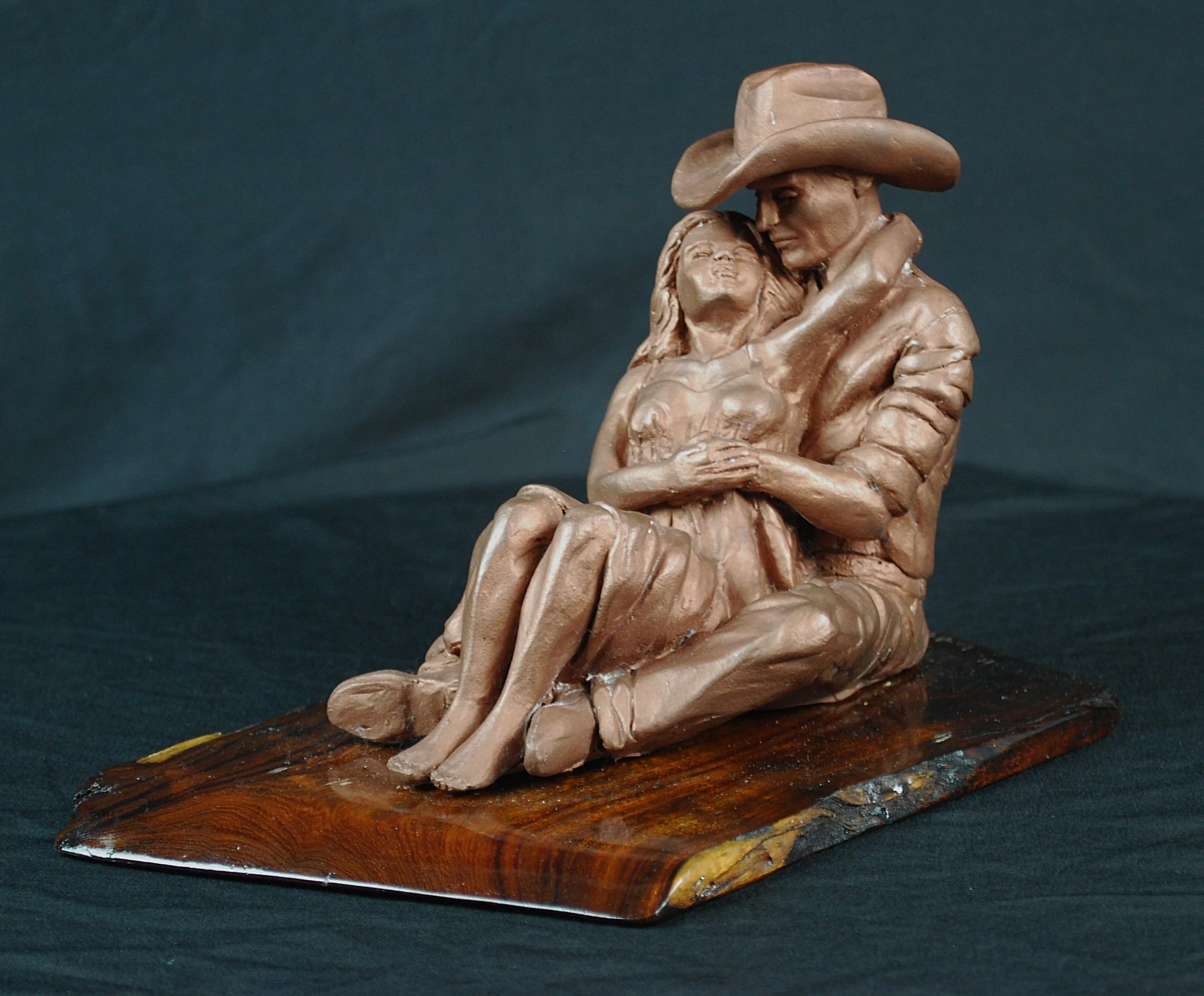 Cowboy Couple sculpture by Sharon Cruson, front three-quarter view of seated Western couple on wood base