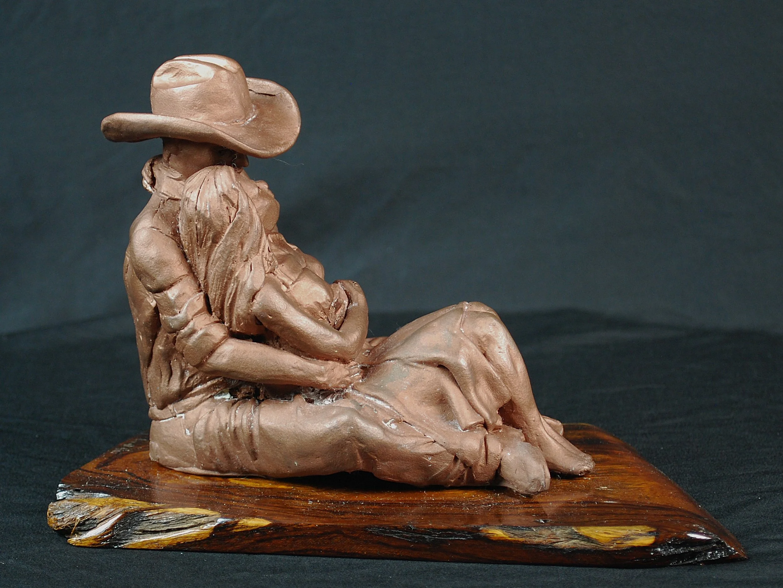Cowboy Couple sculpture by Sharon Cruson, alternate front angle showing the couple embracing on wood base