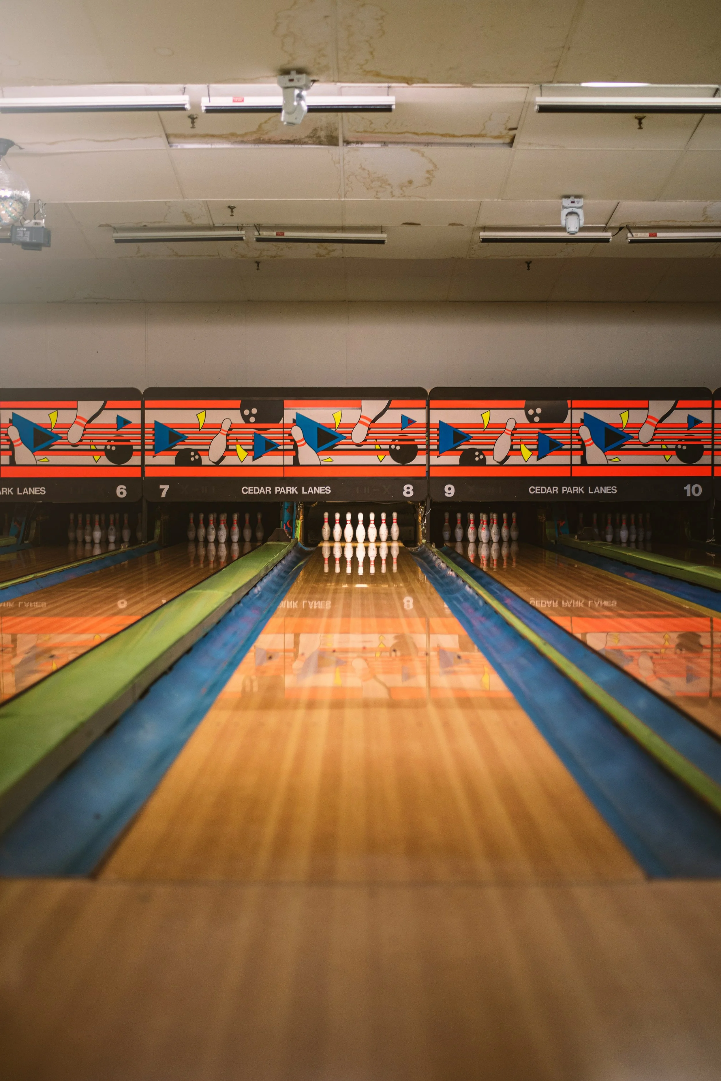 Bowling alley with wooden lanes, colorful lane separators, and arranged pins at the end.