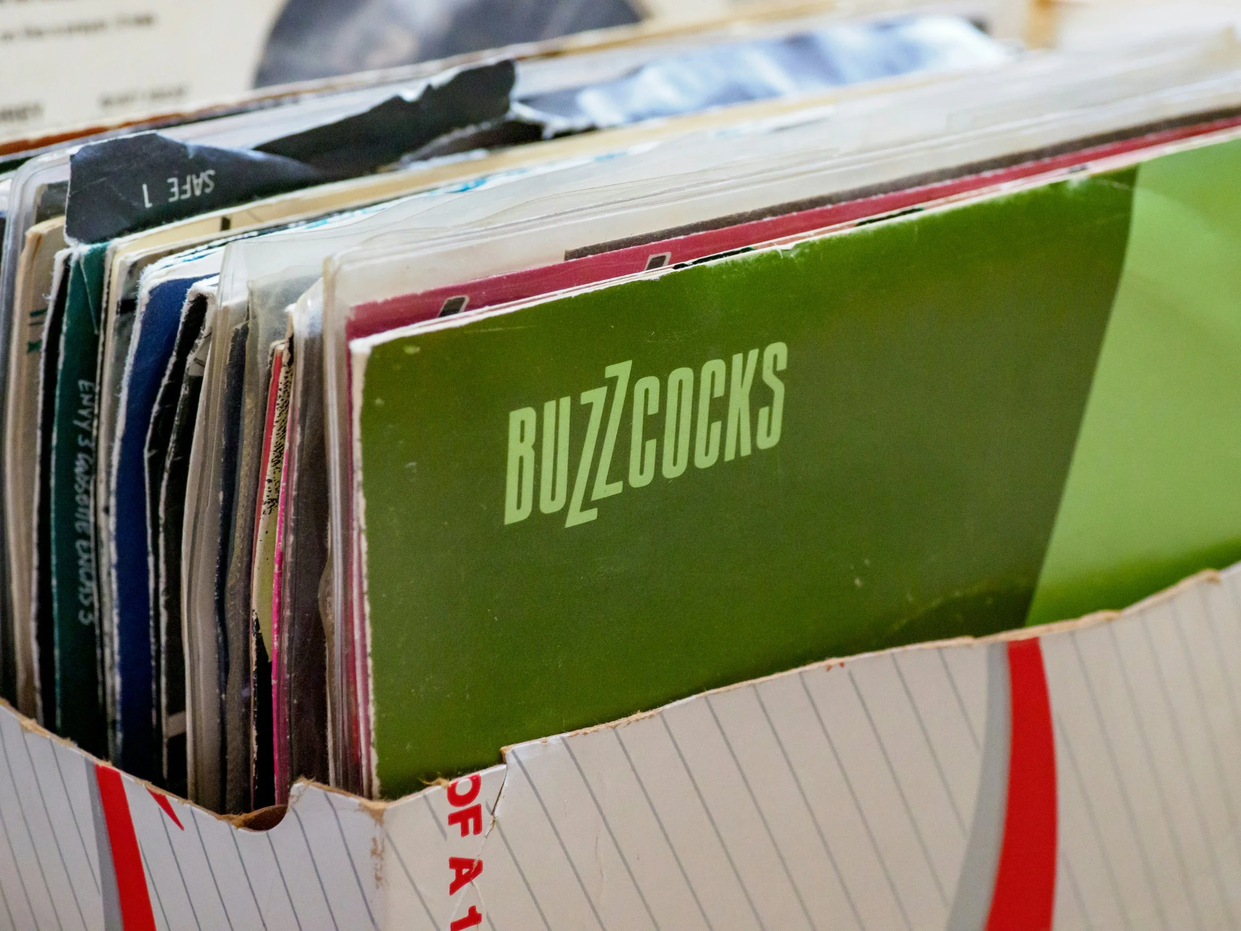 Box of vinyl records with one featuring 'Buzzcocks' cover.