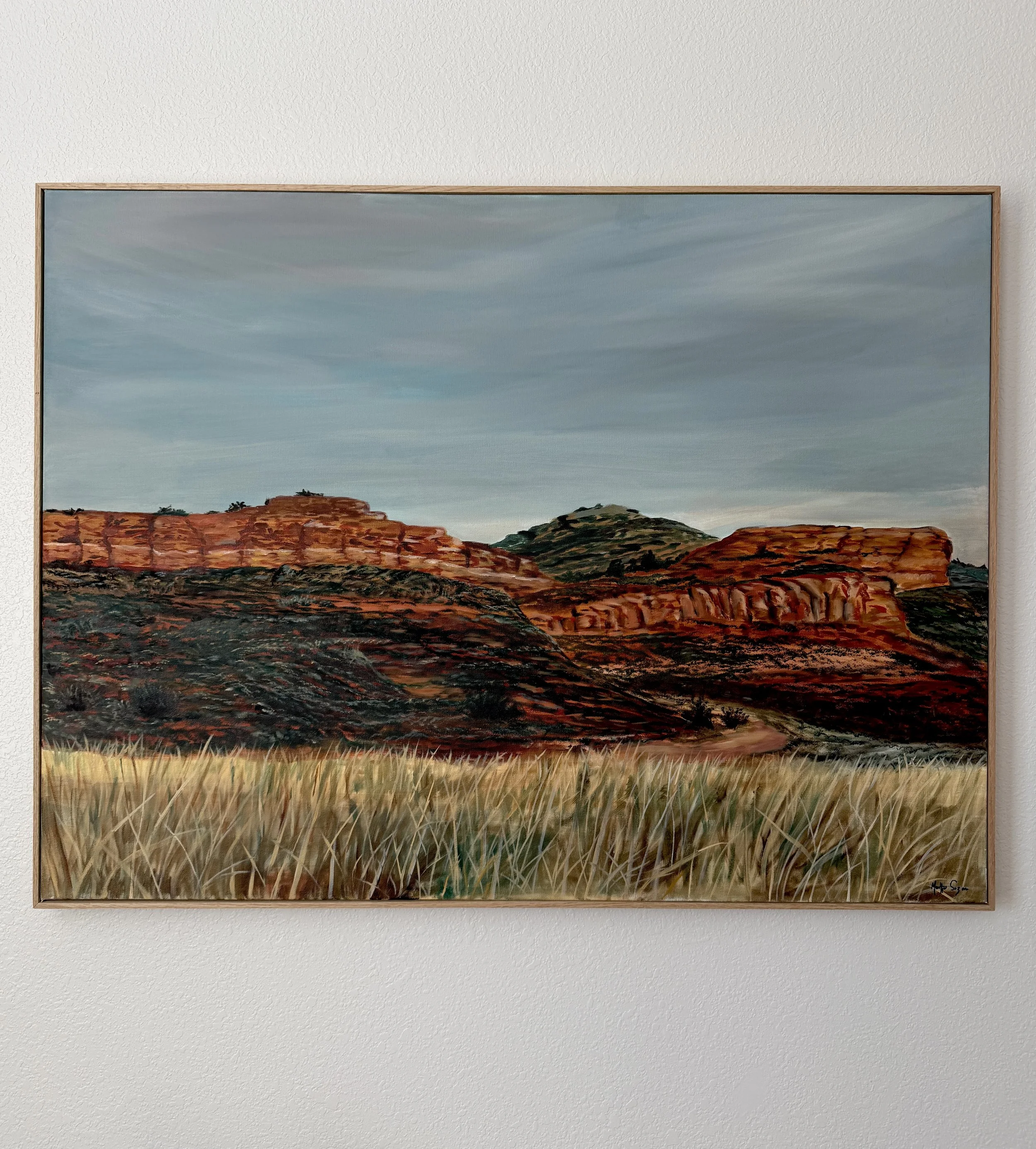 Landscape painting of Colorado foothills depicting red rock formations, green hills, and a sky with soft clouds.