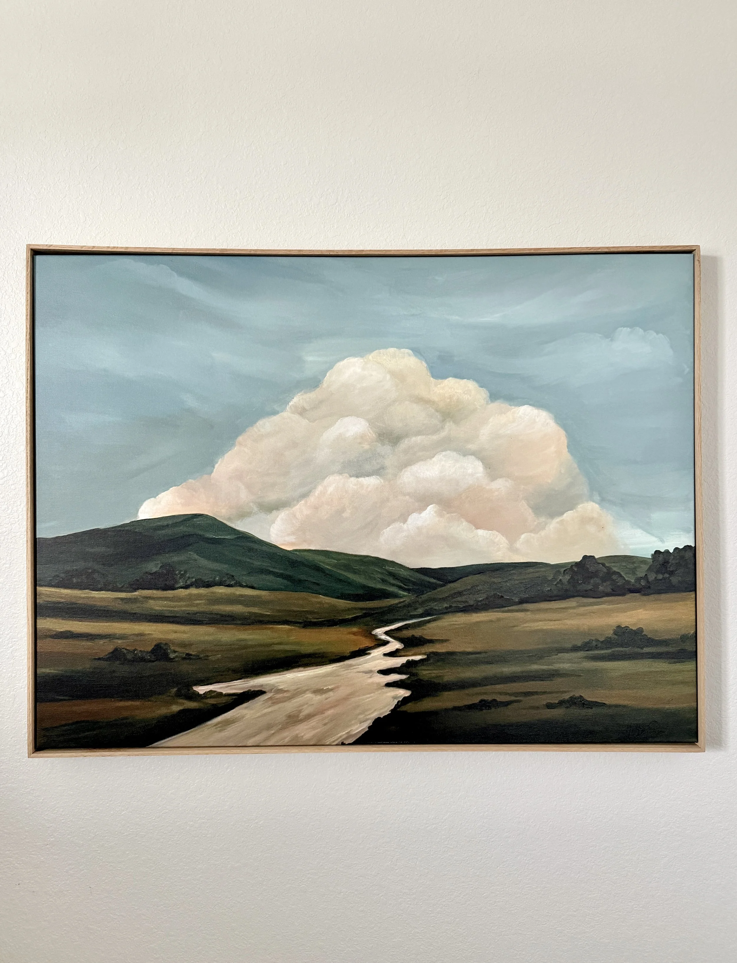 Modern contemporary landscape painting of rolling green hills, a winding stream, and a large cloud in a blue sky.