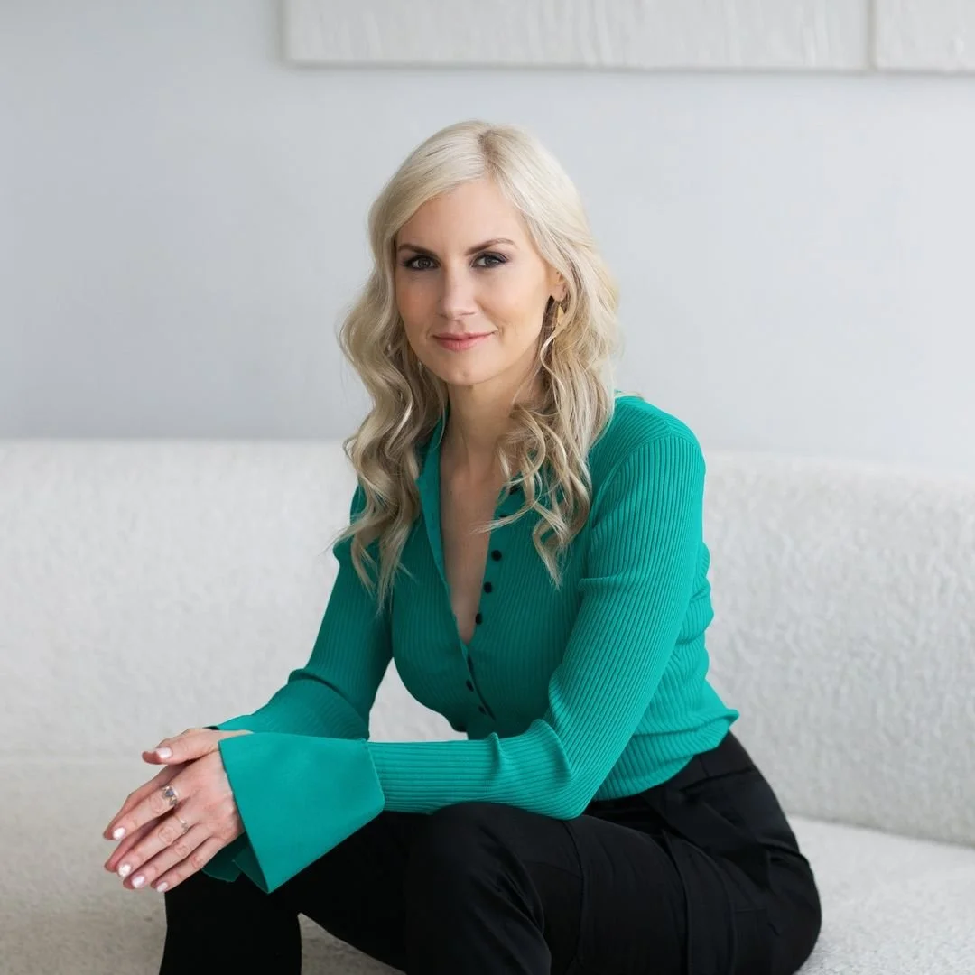 Sloane sitting on white background wearing a teal blouse