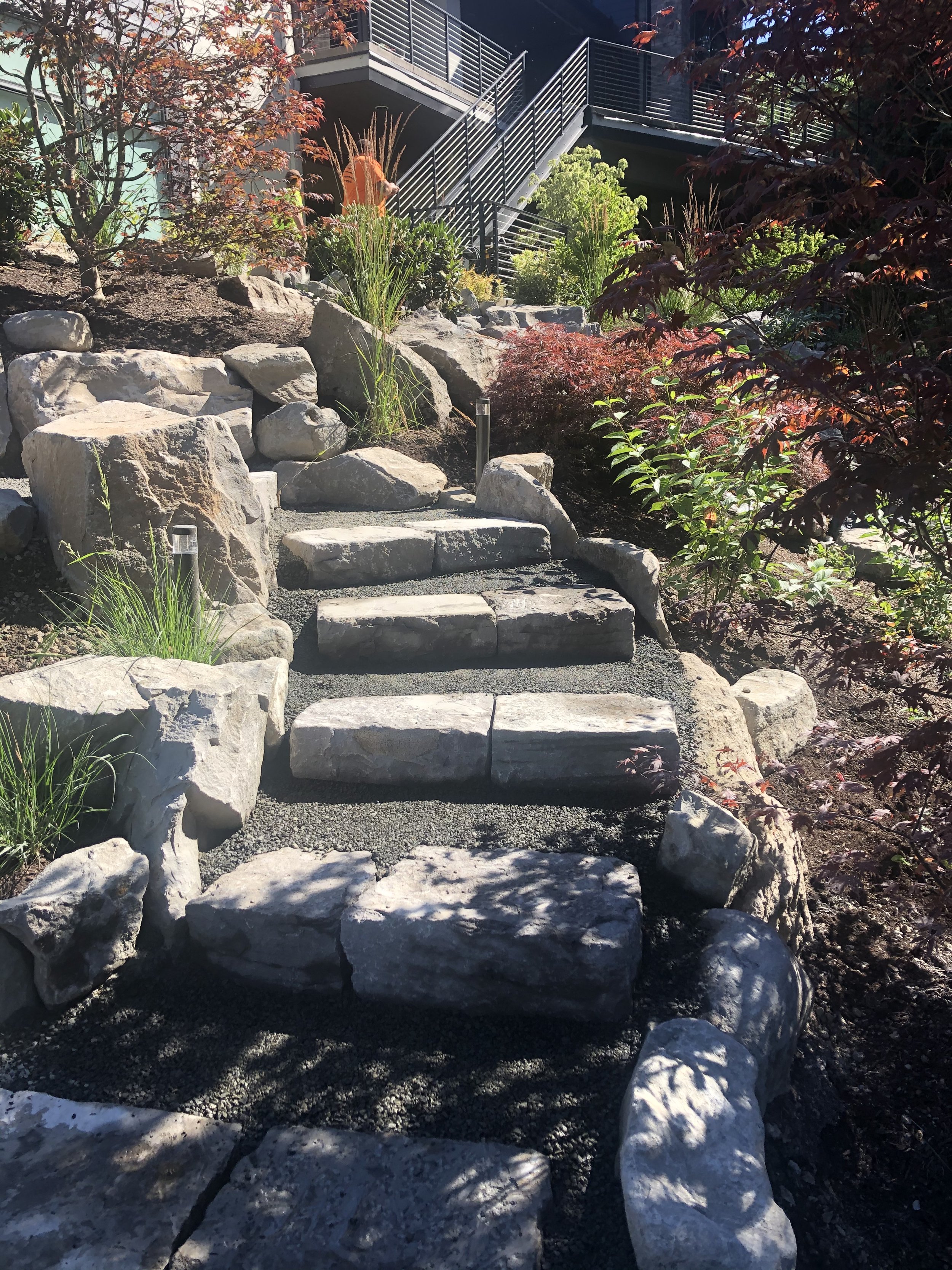 Stone staircase leading to a garden with lush greenery and colorful flowers.