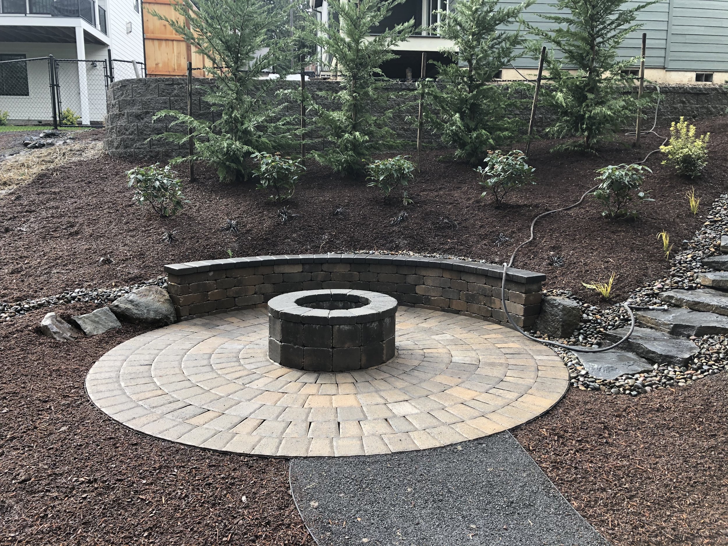 Backyard fire pit with stone sitting, perfect for cozy evenings outdoors.