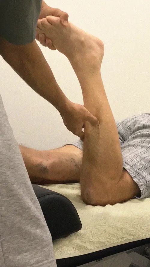 A sports massage therapist in Liverpool works on a client's calf muscle.