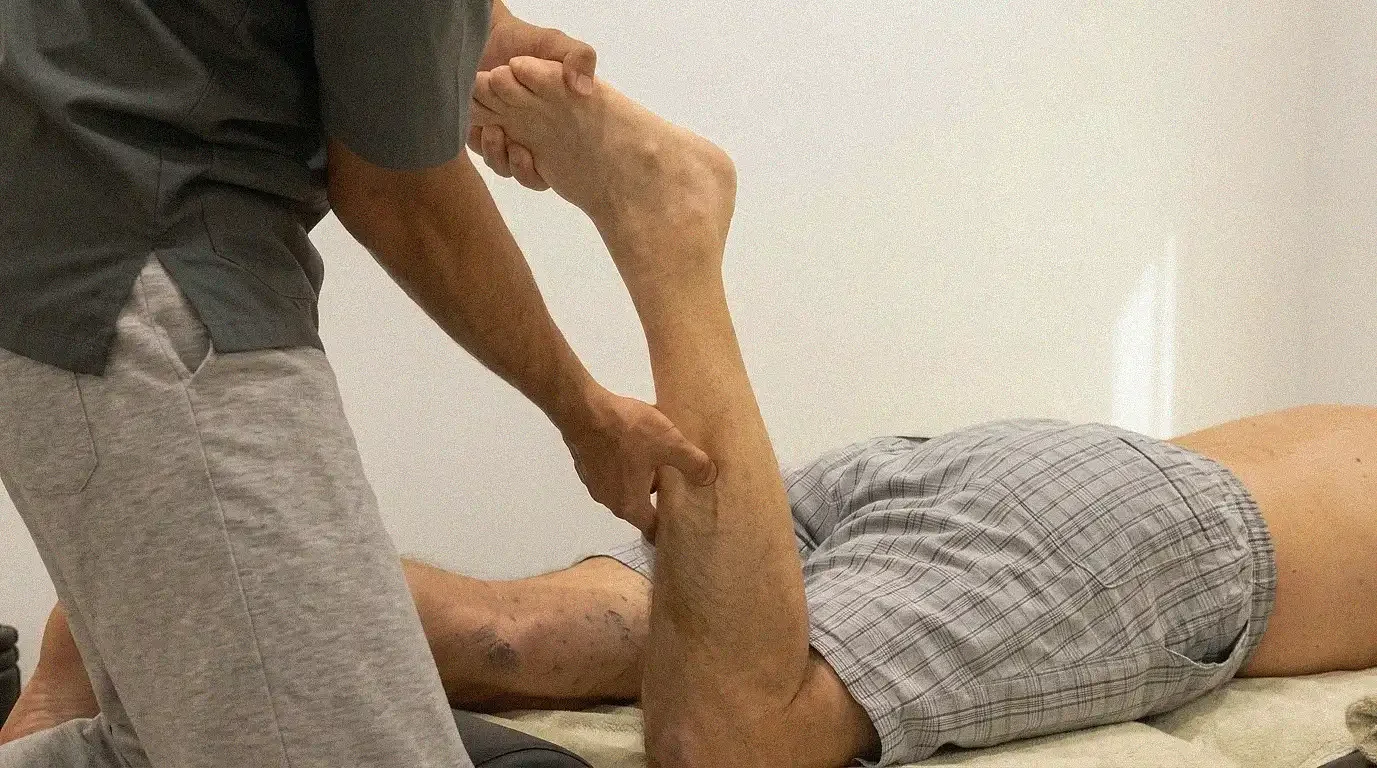 Sports massage therapist working on an athlete’s calf during a hands-on treatment session.