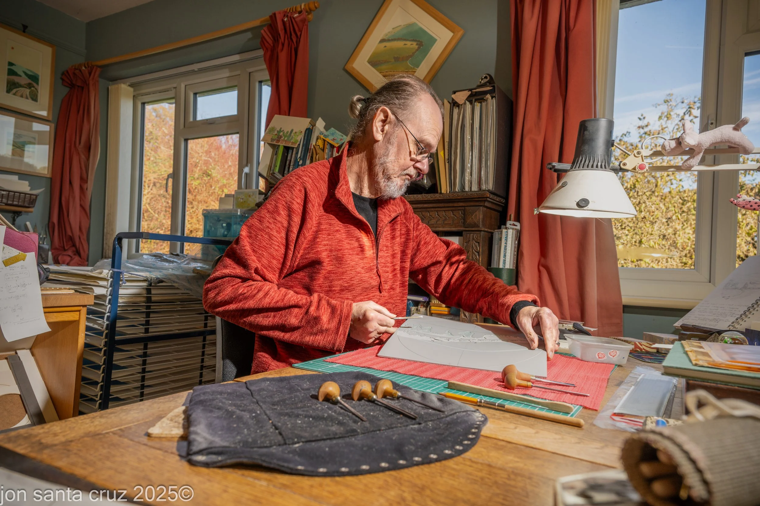 Ian O'Halloran, Artist Printmaker, at his studio desk carving an image into a lino block