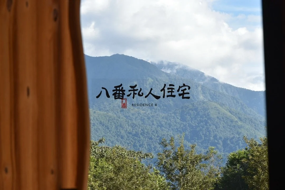 View of green mountains through window with wooden frame, displaying Japanese characters and the words Residential 8.