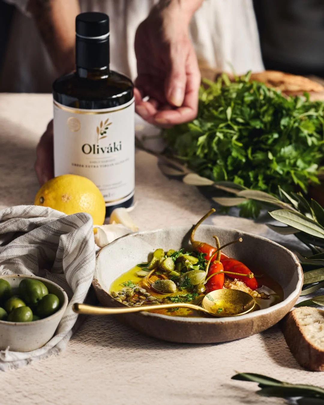 angled image of dipping oil in bowl with girl reaching to olive oil at back