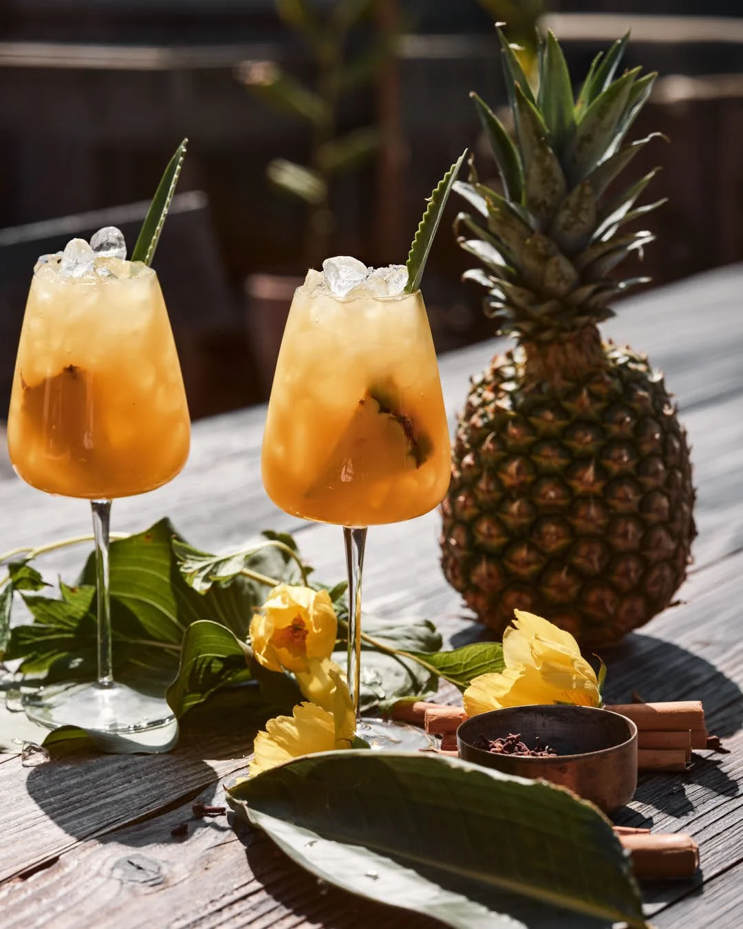 image of two cocktail in summer sun with pineapple and peony flowers in bright summer sun