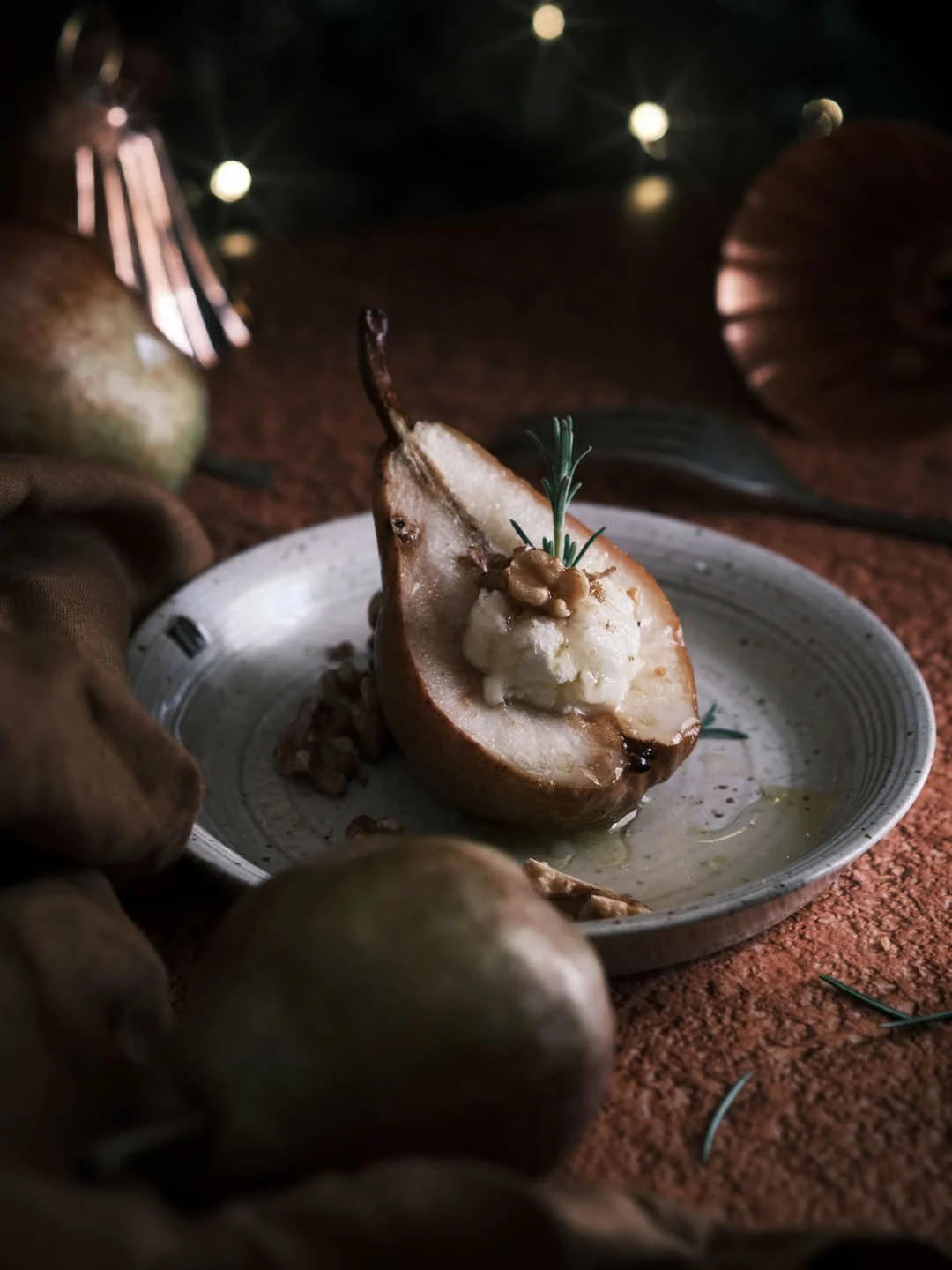angled image of roast pear in festive scene with mascarpone, walnuts and honey