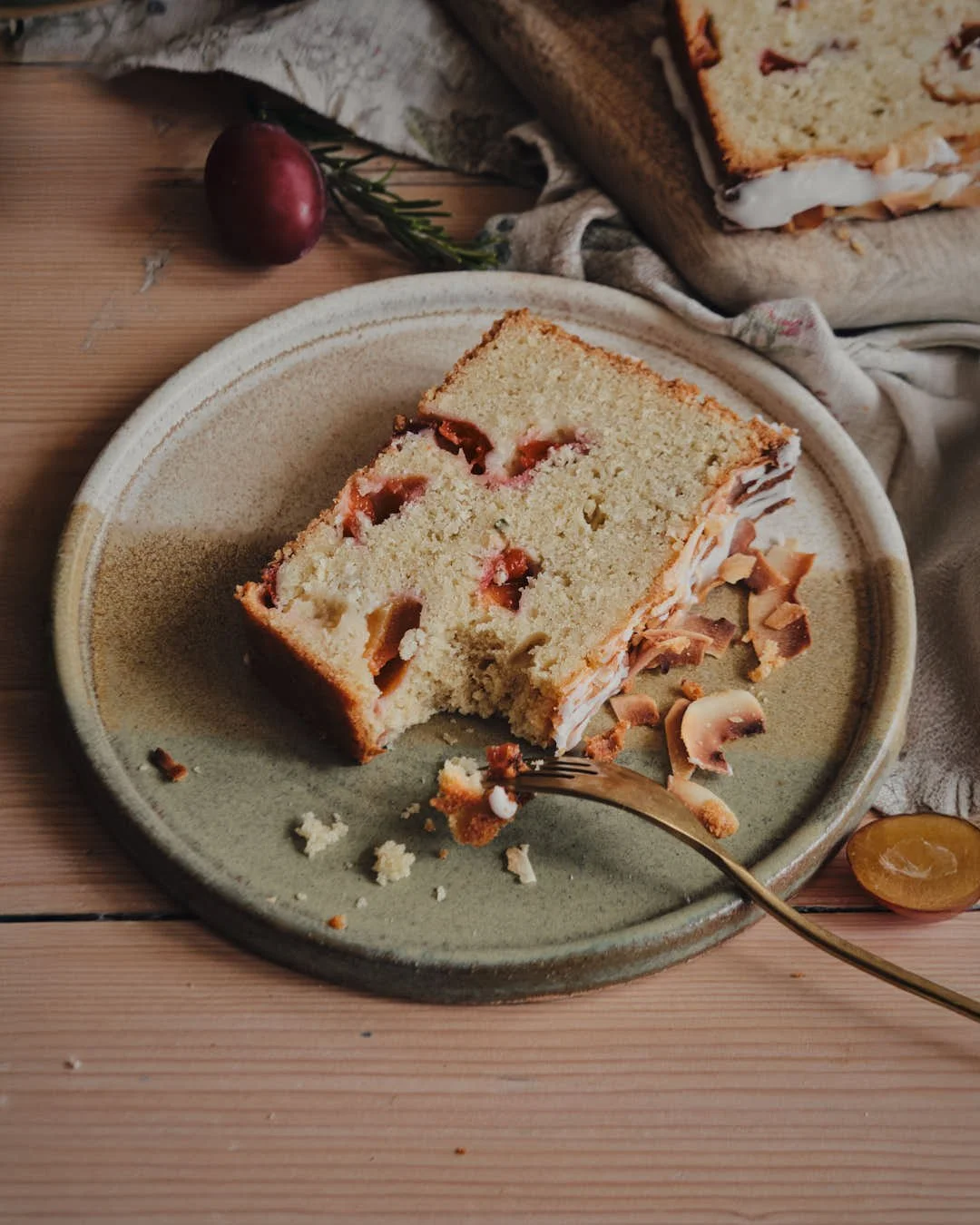 angled overhead image of slice of fruit studded loaf cake in warm farmhouse setting
