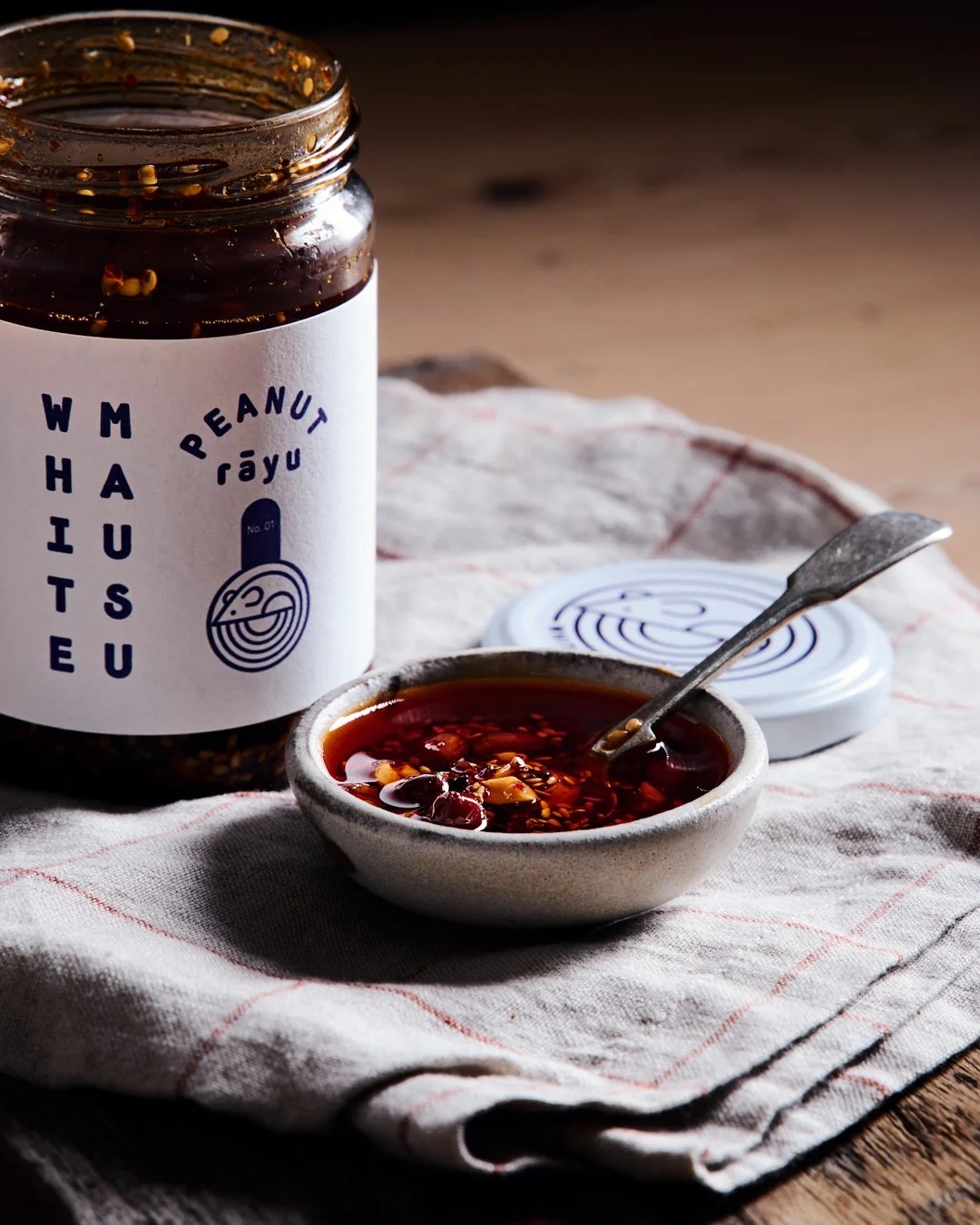 angled image of chilli oil in bowl with jar to side in moody lit scene