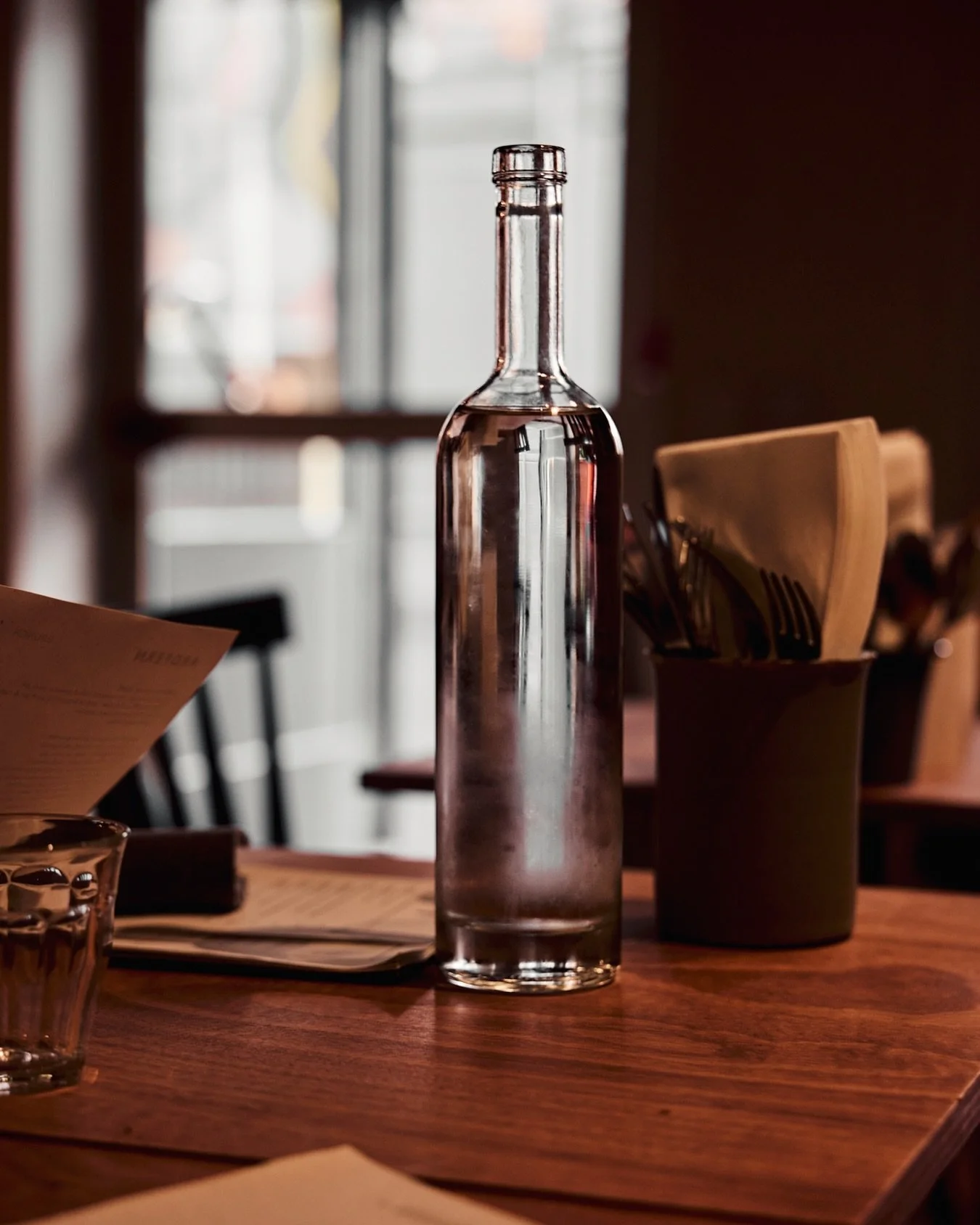There&rsquo;s a quiet beauty in the in-between moments &mdash; the pause before the first sip, the soft clink of cutlery, the hum of a restaurant easing into its evening rhythm. I love how the light catches this chilled bottle, turning something so s