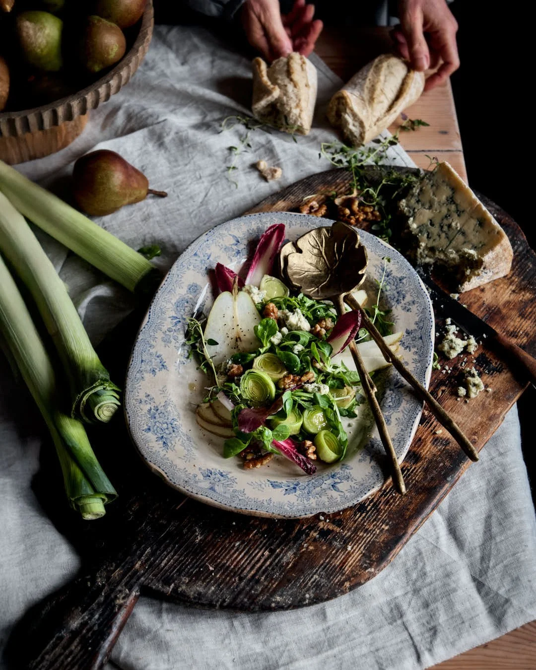fangled image of leek and pear sald on blue patterened plate in rustic winter kitchen scene