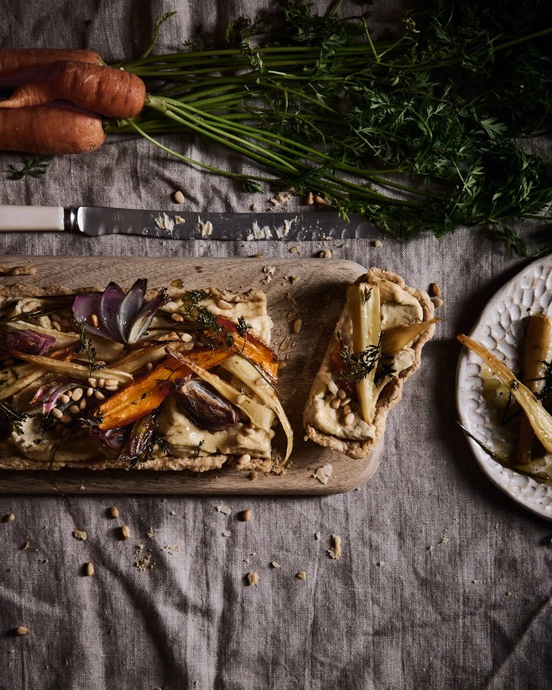 A rustic red lentil hummus tart, layered with slow-roasted roots, sweet caramelised onions and a scattering of pine nuts &mdash; humble ingredients transformed into something quietly beautiful.

Earthy, nourishing, and made to be savoured slowly at t