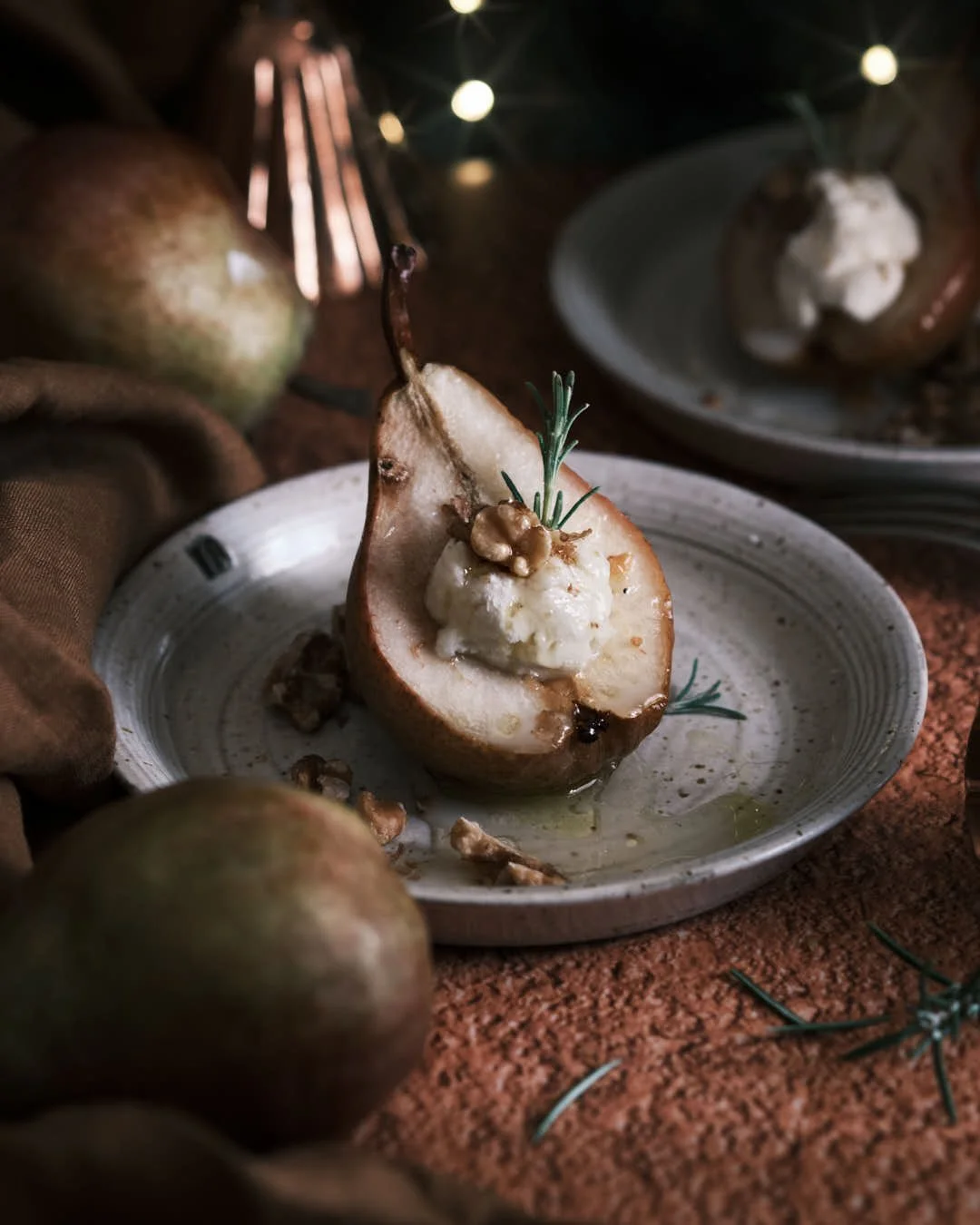 angled image of roast pear in festive scene with mascarpone, walnuts and honey