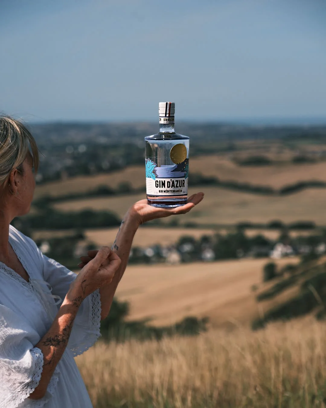 girl holding gin bottle against backdrop of stunning sky
