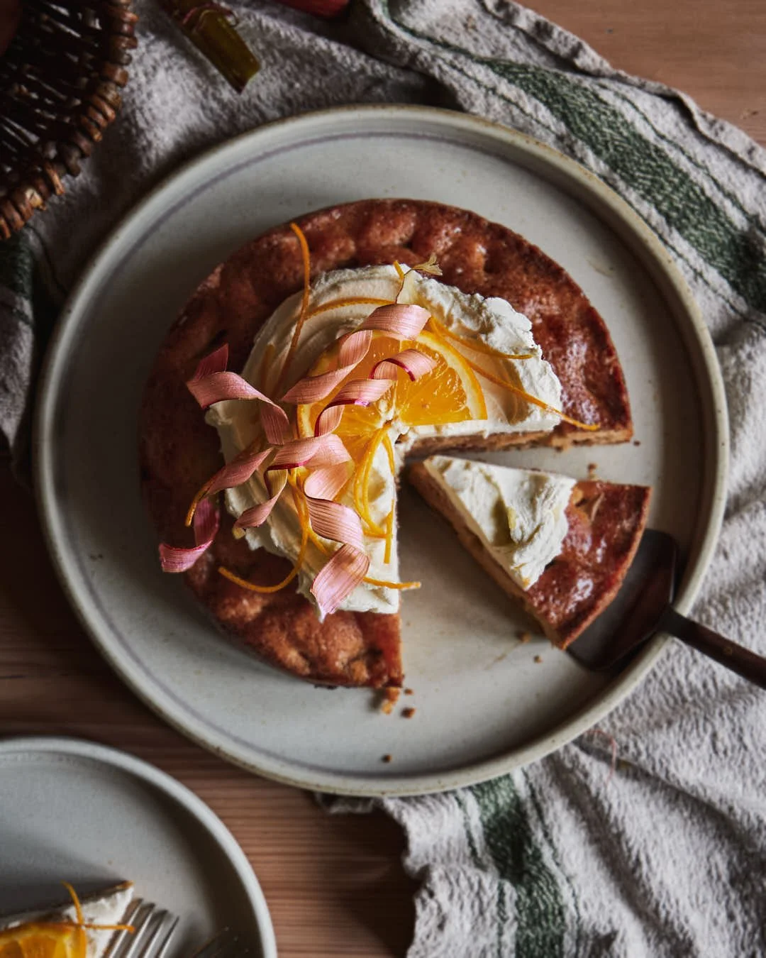 angled image of cake with mascarpone, orange and rhubarb curl garnish