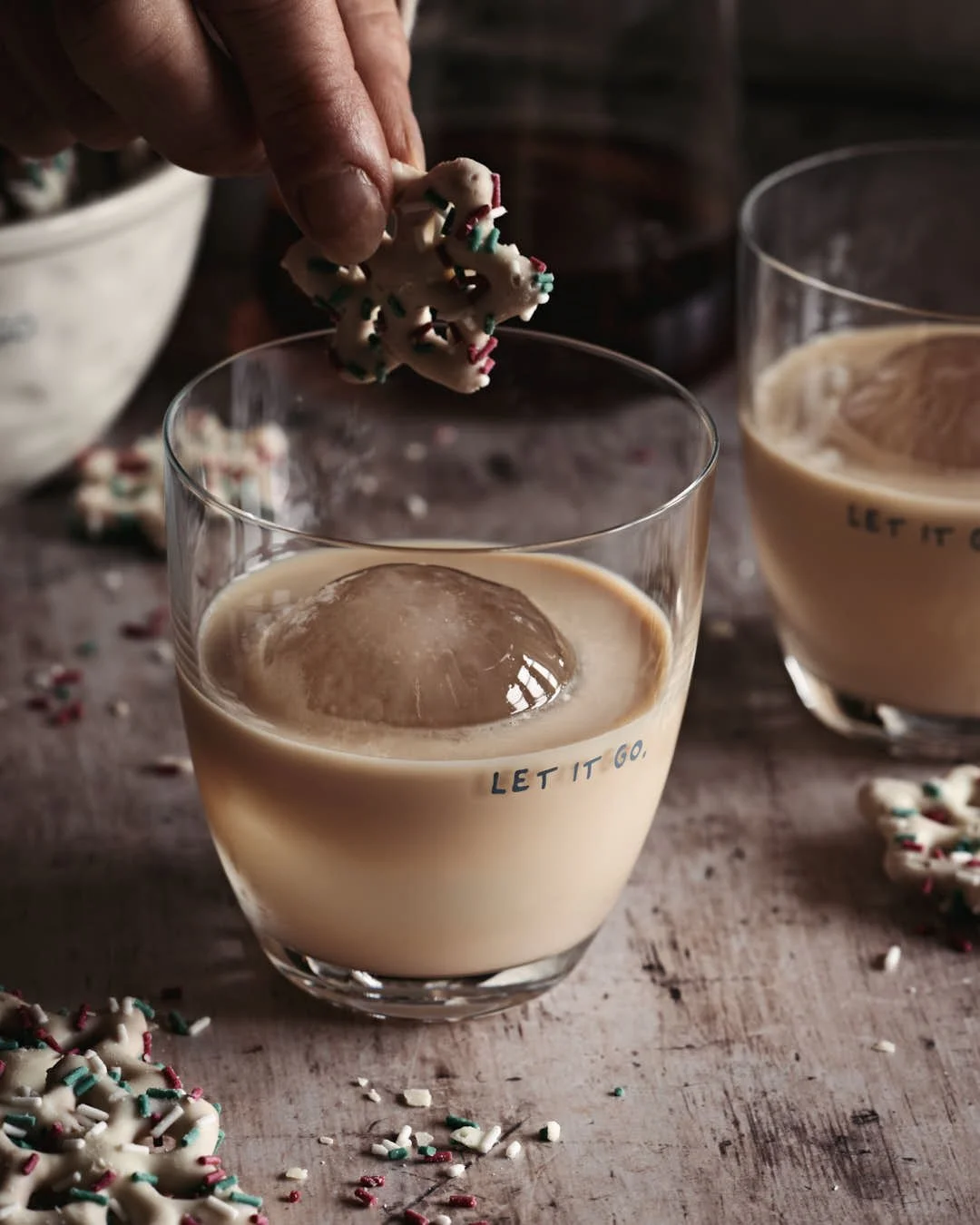 hand going to dunk white chocolate pretzel into glass of rum cream in winter moody scene