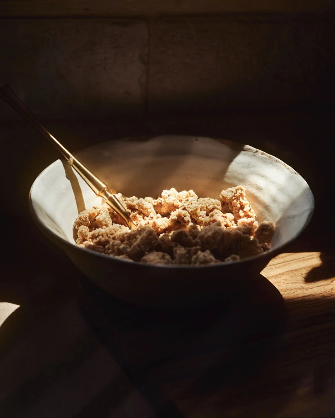 bowl of streusel in chiaroscuro on wooden board