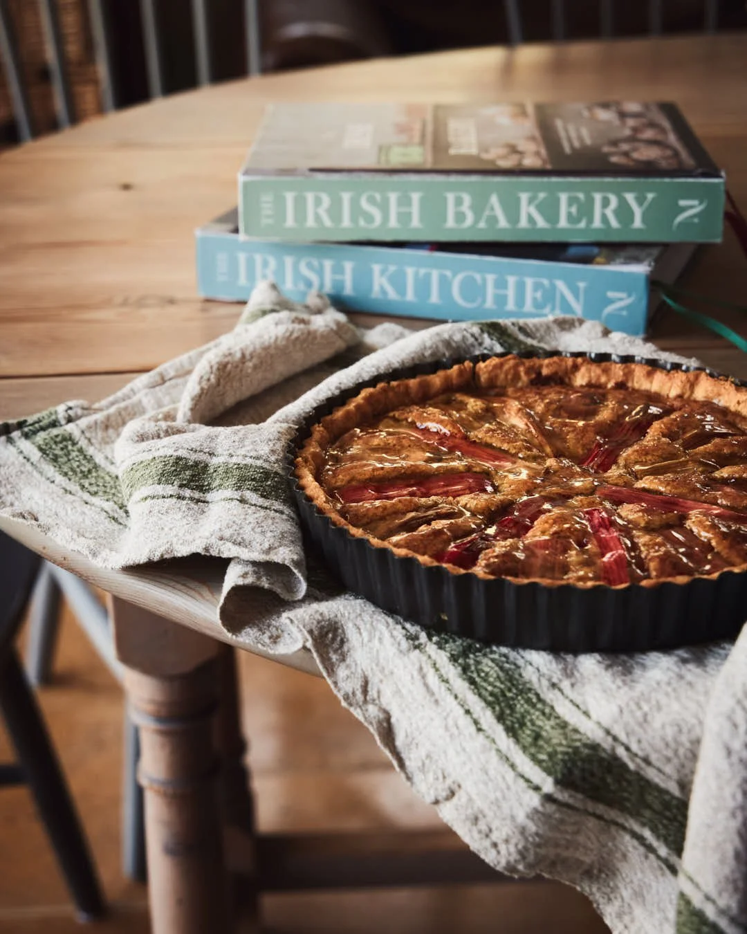 rhubarb tart on table with cookbooks behind