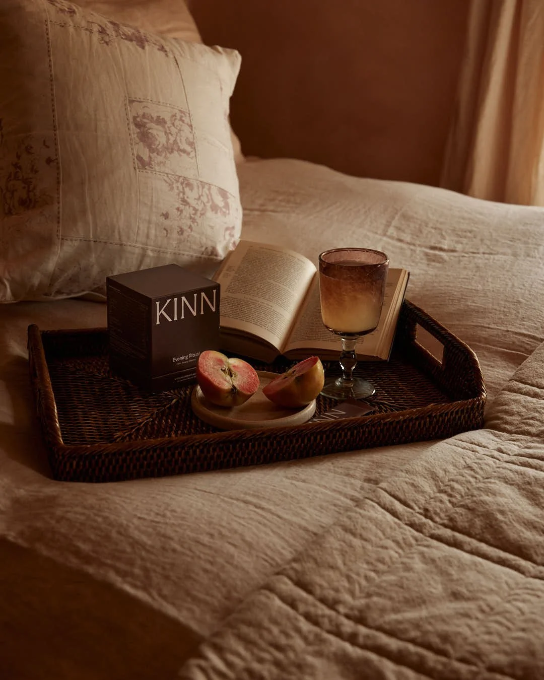 angled image of tray on bed with cozy apple and glass in scene
