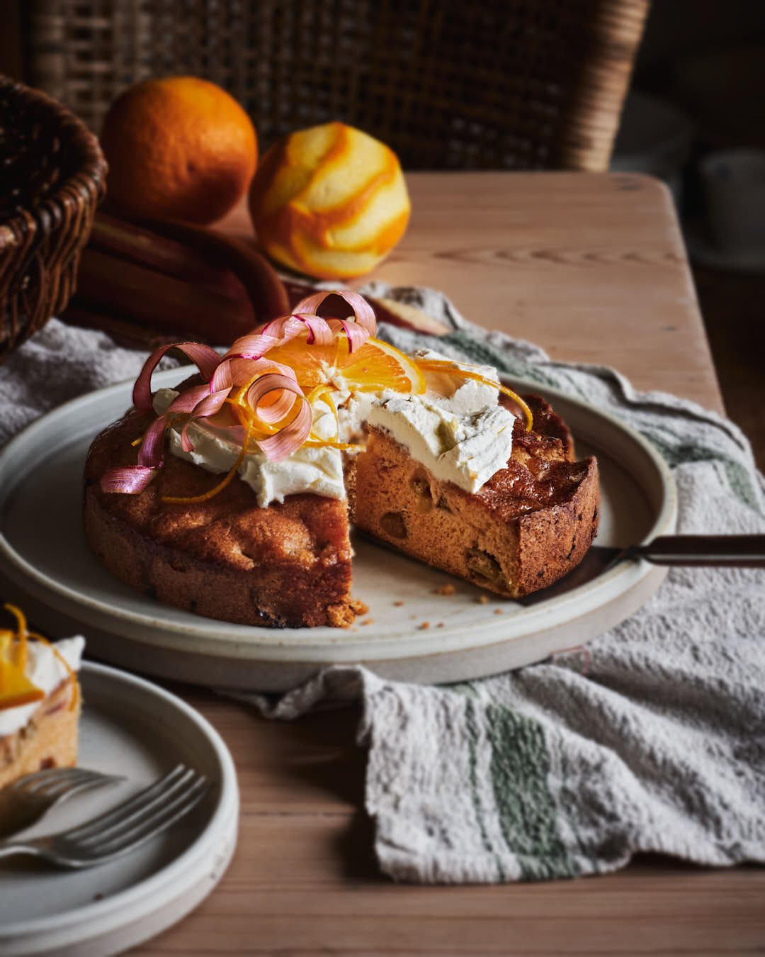 angled image of cake with mascarpone, orange and rhubarb curl garnish