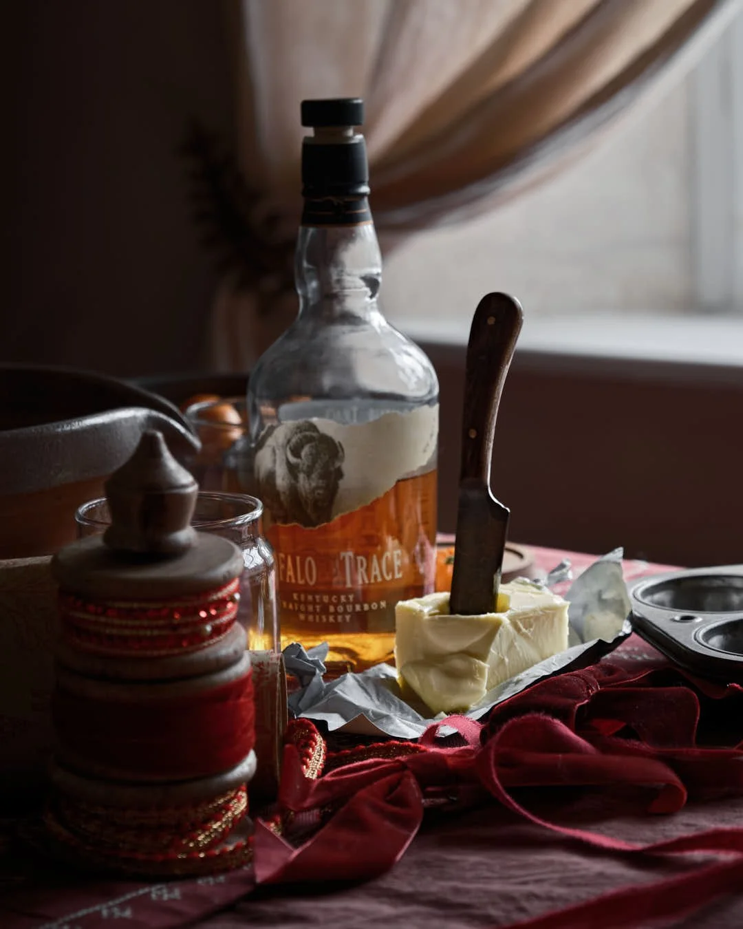 macro image of knife in butter with bourbon bottle to back