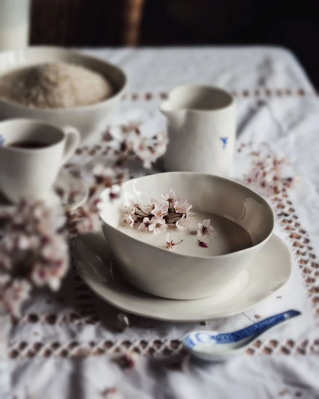 angled overhead image of amazake in a bowl with cherry blossom