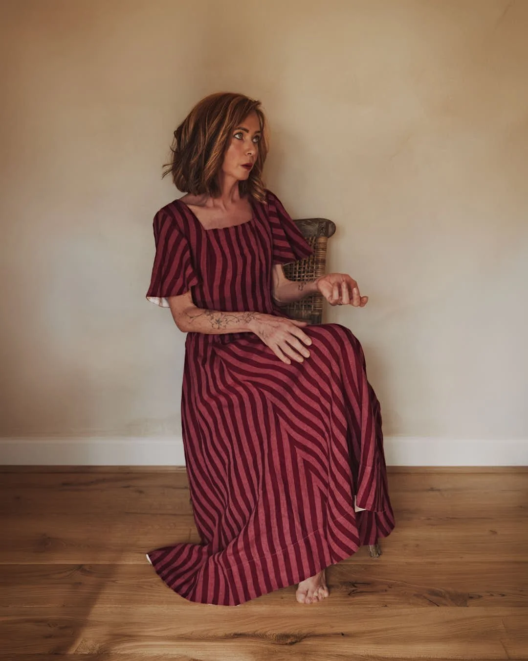 girl in red dress holding out empty hand with surprised look in stunning vintage scene with warm walls