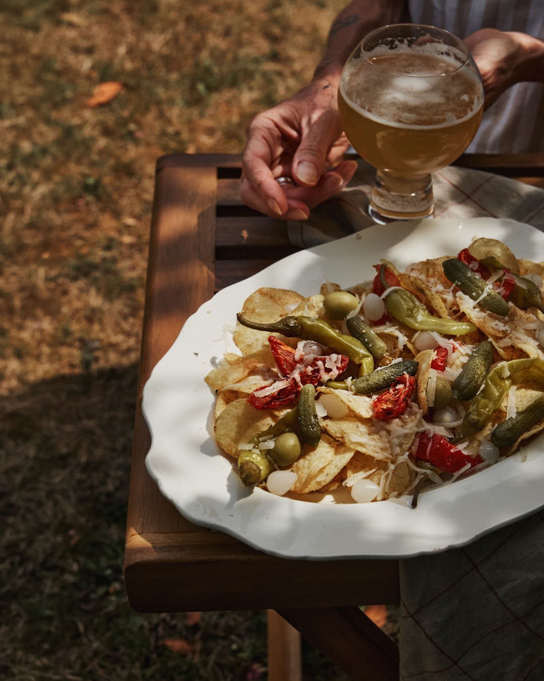 angled image of cream vintage platter with crisps topped with array of charcuterie with pickles and cheese