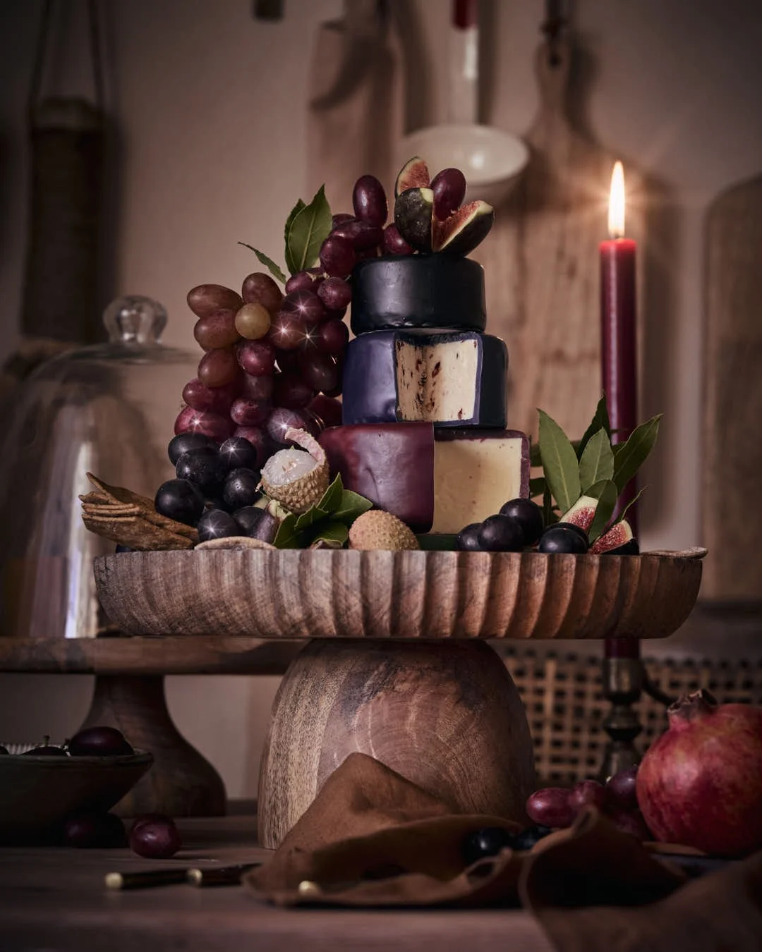 tower of wax coated cheese in candlelit scene on wooden stand with festive vibes