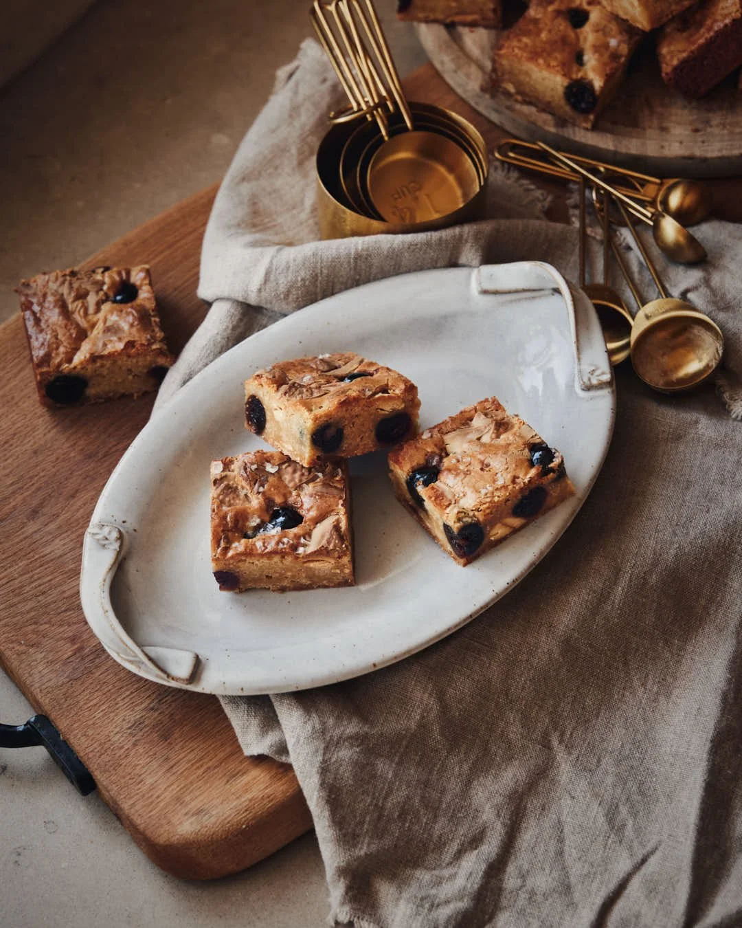 stunning plate of blondies in rustic 45 overhead shot with gold measuring spoons and linen cloth