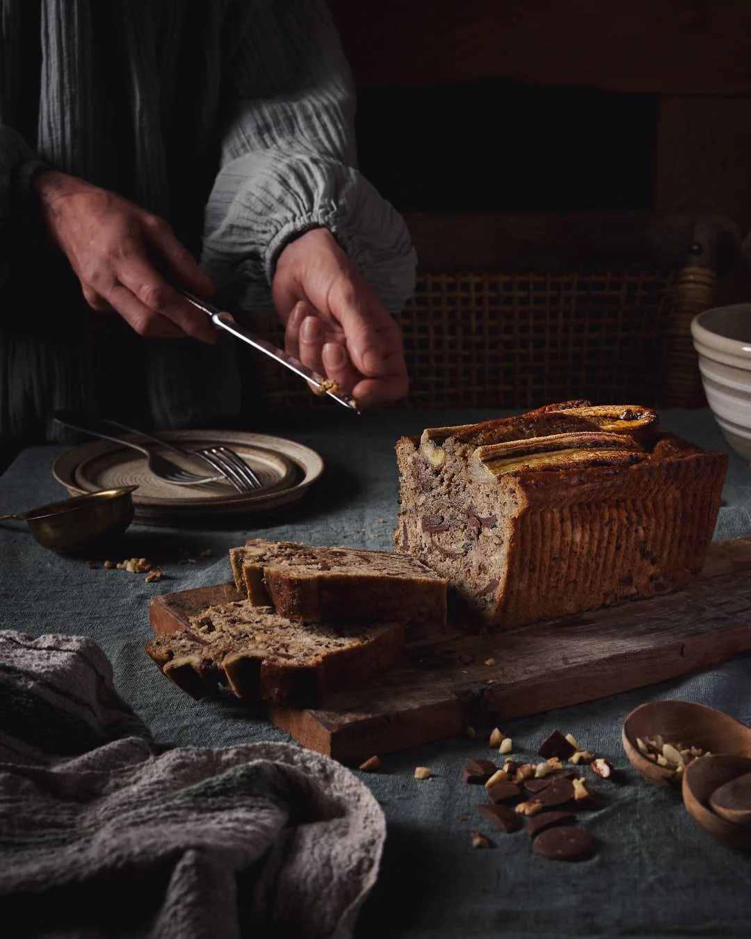 straight on image of girl reaching to cut banana loaf in moody scene