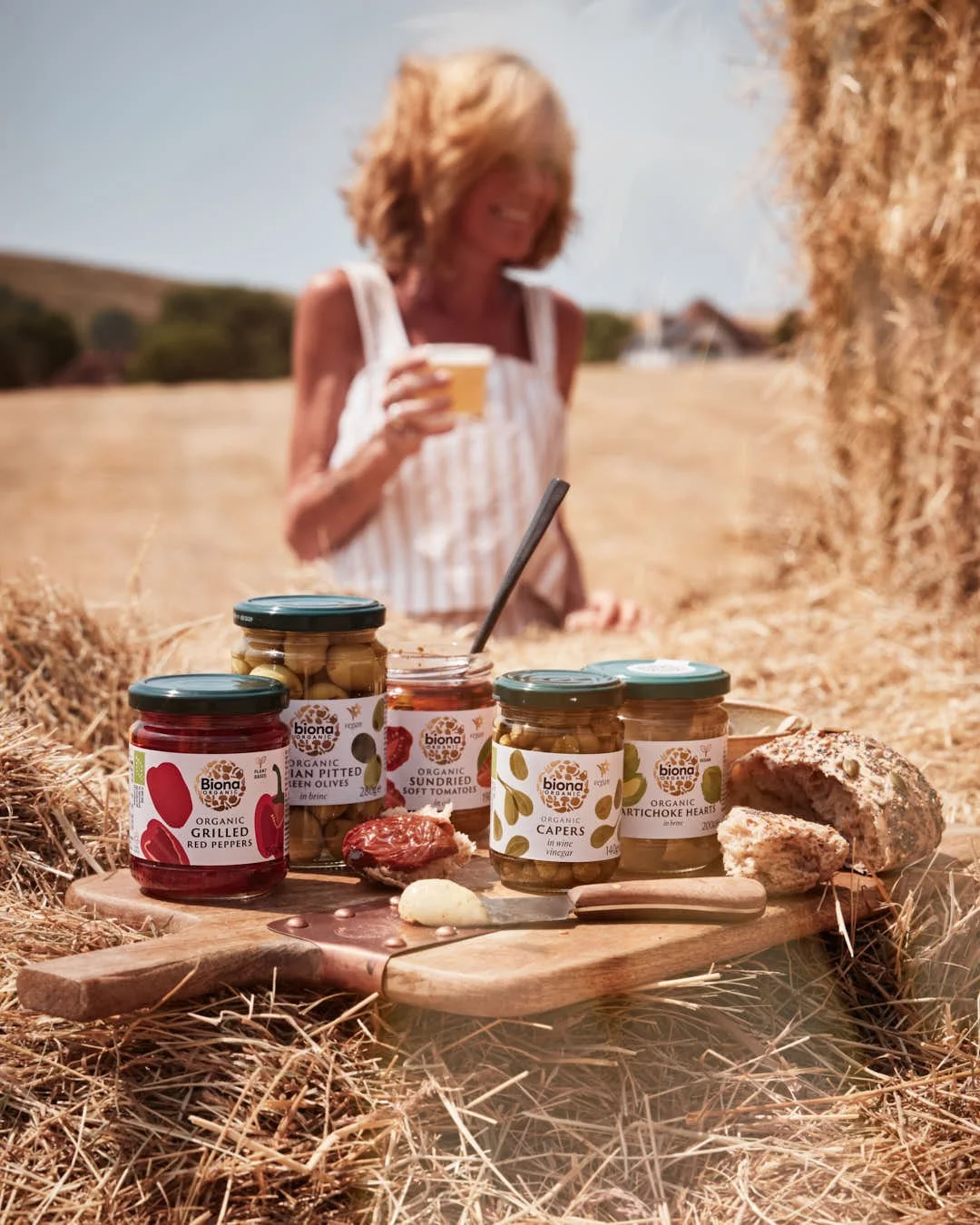 girl with beer in front of antipasti jars on hay bales