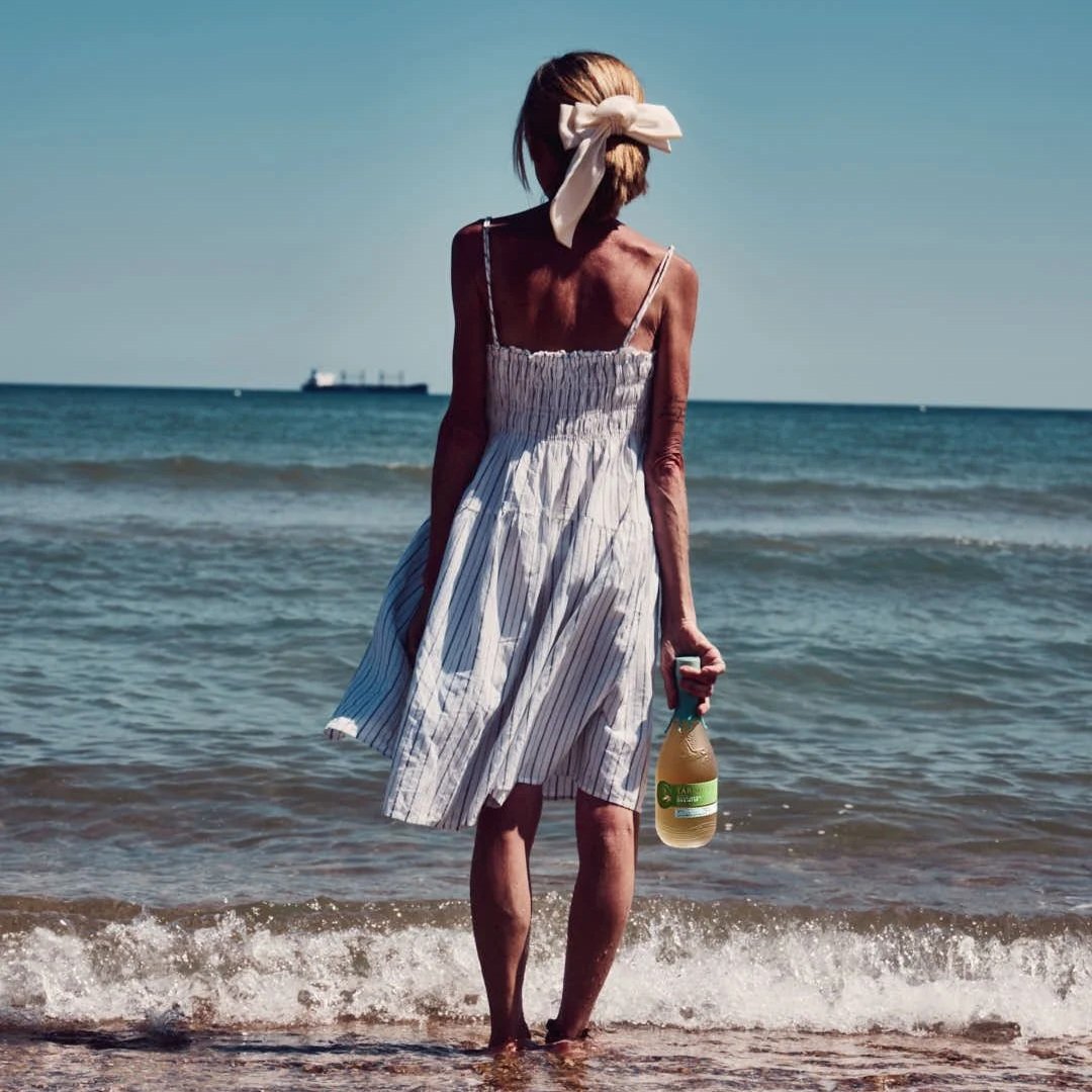 girl standing with bottle in sea in summer dress