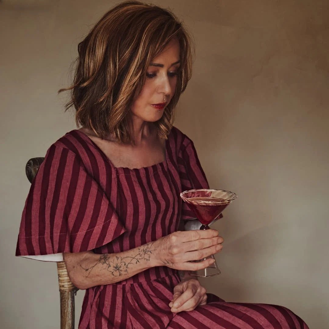 girl in red and pink linen dress contemplating red hued martini