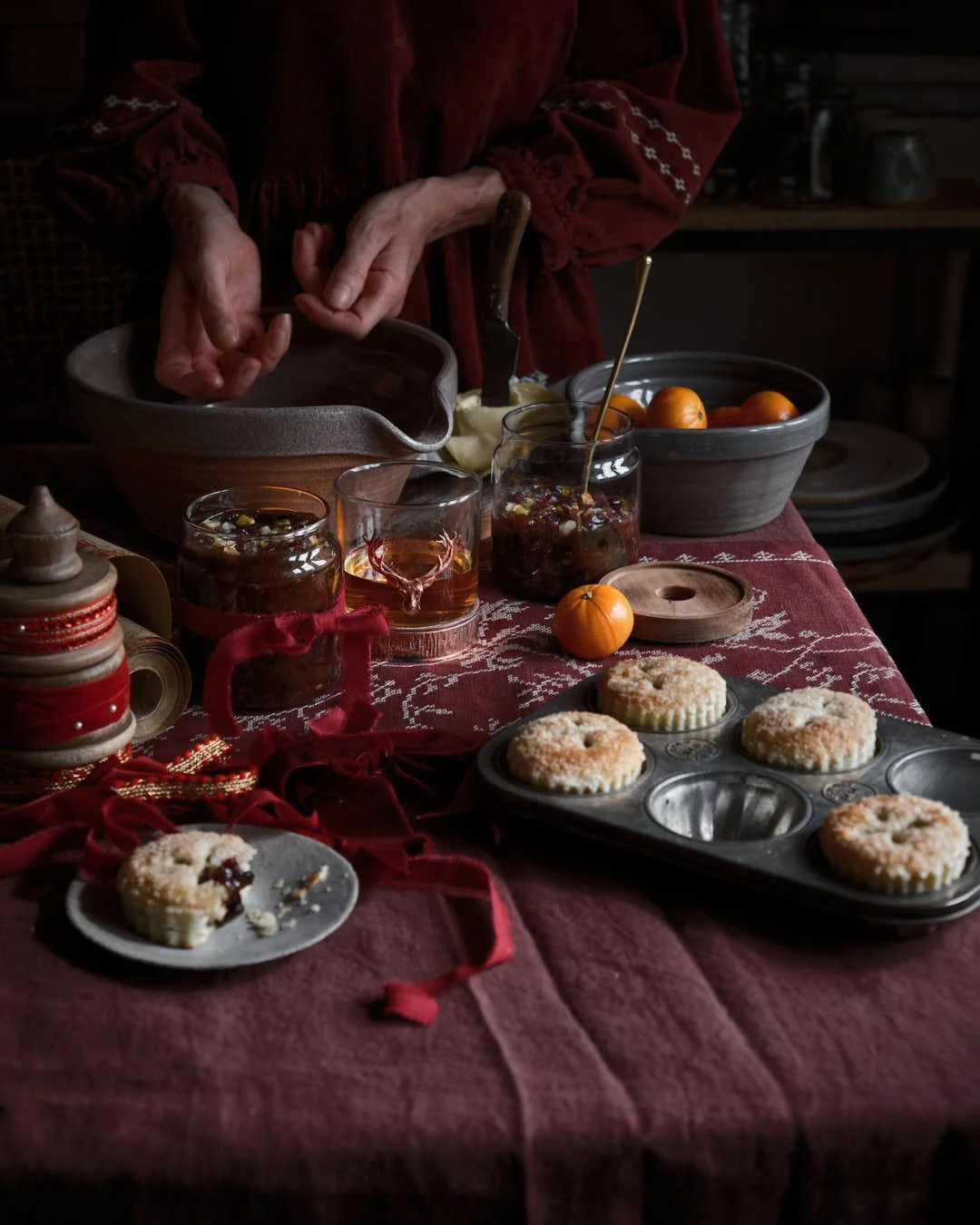 girl outting hand to mixing bowl at back of scene with oranges and mince pies