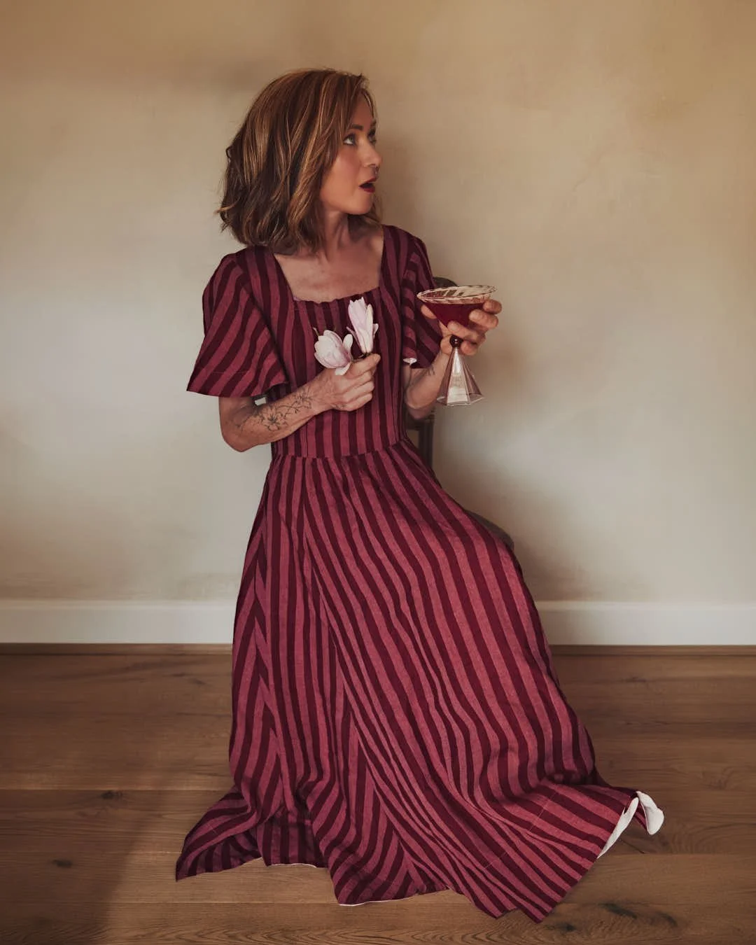 girl in red striped dress contemplating martini with surprised look in warm vintage scene