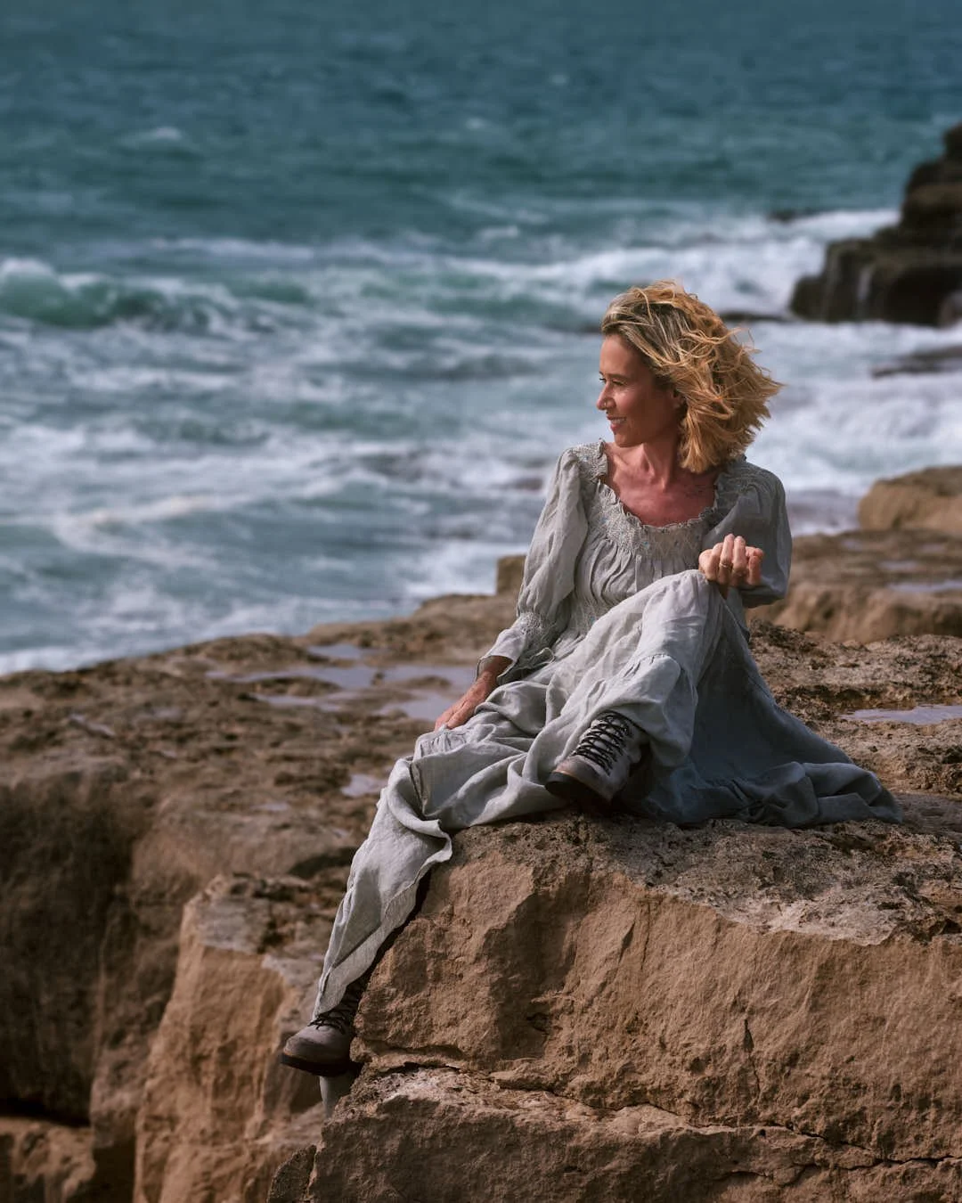 girl sitting on rocks in stunning blue green linen dress